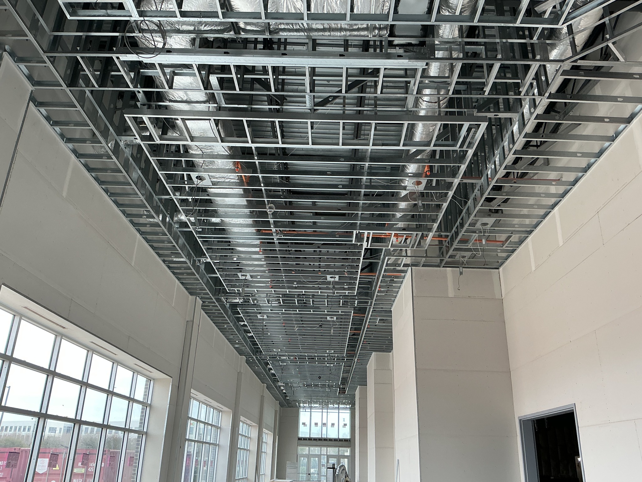 Metal ceiling framing above a corridor with drywall walls